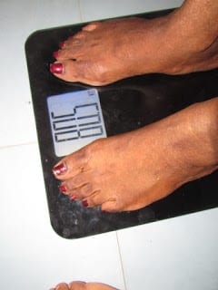 Standing on a weighing scale to record my weight loss progress